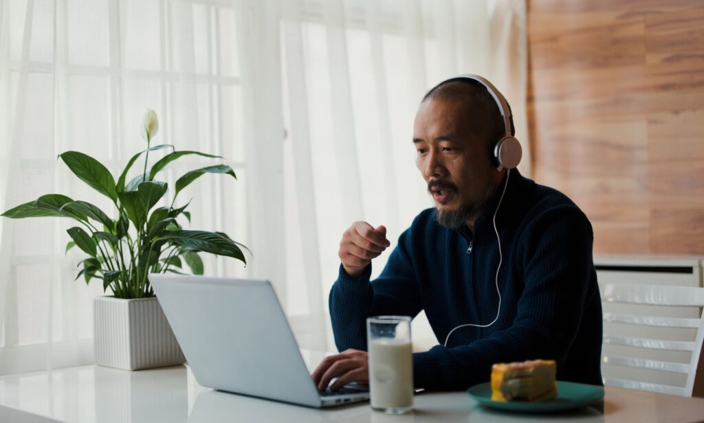 Adult man having video conference with laptop at table in morning